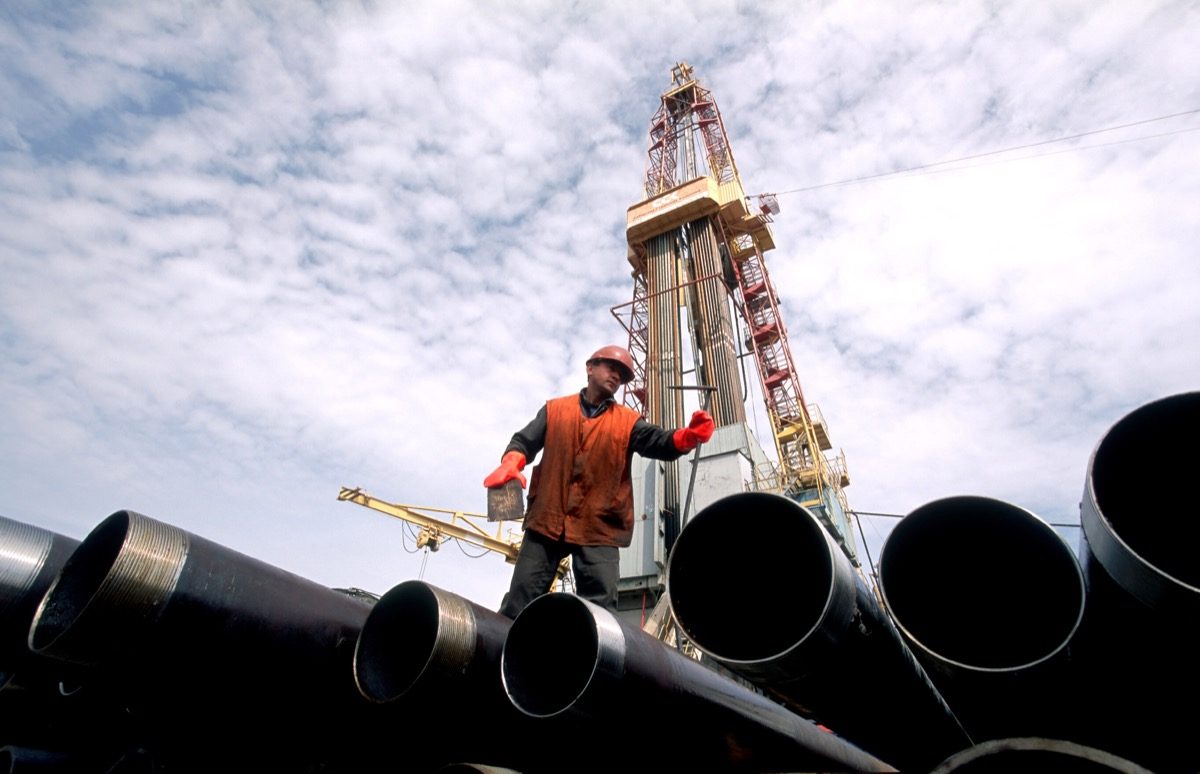 Oil Field worker on oil pipes in front of oil rig