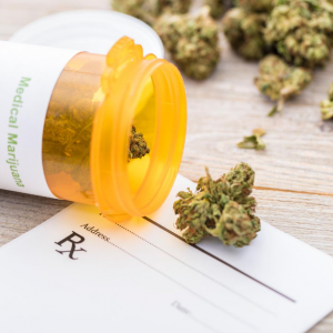 Marijuana buds spilling out of prescription bottle on top of Rx pad