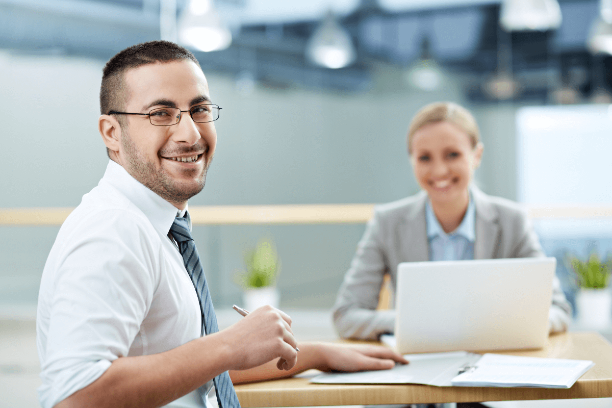 Employees smiling sitting on desk working on invoicing