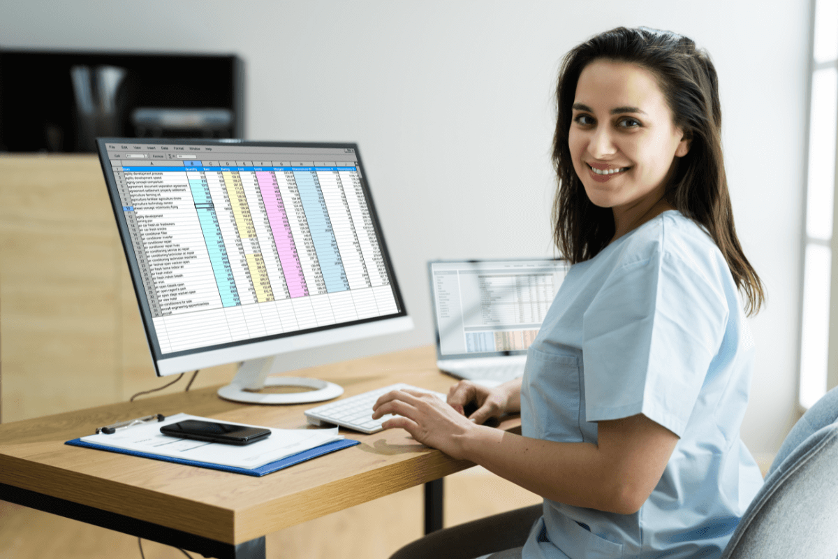 Female medical employee on computer desk managing spreadsheet data